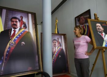 CODEPINK activist Medea Benjamin speaks to reporters, surrounded by pictures of former President of Venezuela Hugo Chavez and current president Nicolas Maduro, near the entrance of the Venezuelan embassy in Washington, DC on April 19, 2019. - Activists opposed to supporters of Venezuelan opposition leader Juan Guaido and their takeover of diplomatic buildings belonging to the Venezuelan government of Nicolas Maduro have been staging a 24/7 vigil to protect the Venezuelan Embassy in Washington DC. (Photo by Andrew CABALLERO-REYNOLDS / AFP)