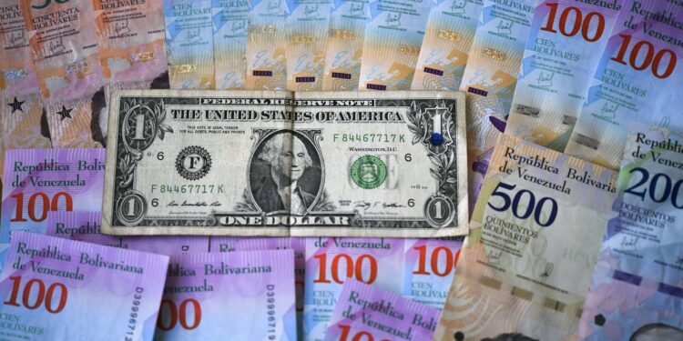 This ilustration shows Venezuelan Bolivar banknotes and a US one-dollar bill in Caracas on January 28, 2019. - Venezuela devalued its currency by almost 35 percent on Monday to bring it into line with the exchange rate of the dollar on the black market. The exchange rate is now fixed at 3,200 bolivars to the dollar, almost matching the 3,118.62 offered on the dolartoday.com site that acts as the reference for the black market. (Photo by YURI CORTEZ / AFP)
