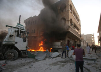 EDITORS NOTE: Graphic content / People walk amidst rubble as part of a building burns following a reported airstrike by Syrian regime forces in  Maaret al-Numan in Syria's northwestern Idlib province on August 28, 2019. (Photo by Abdulazez Ketaz / AFP)