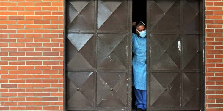 A morgue worker stands behind a half-open door in Barquisimeto, 250 km from Caracas on November 28, 2014. As many as 35 Venezuelan hunger striking inmates have died, a rights group said Thursday, after they drank what prison authorities said was a cocktail of prescription drugs and grain alcohol. AFP PHOTO/SHAMIL CAMEJO