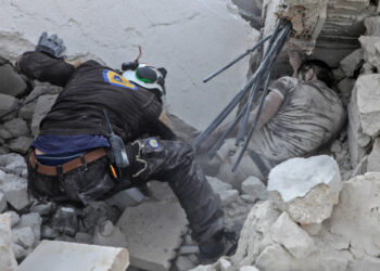 A member of the Syrian Civil Defence (White Helmets) recovers a body from the rubble after a reported airstrike by regime planes on the town of Maaret Hurmah in the southern countryside of Syria's northwestern Idlib province, on August 14, 2019. - An agreement between the United States and Turkey to establish a safe zone in northwest Syria will be implemented gradually, with some operations beginning soon, a Pentagon spokesman said on August 15. (Photo by Abdullah Hammam / AFP)