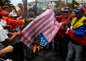 Supporters of the Venezuelan government burn a makeshift US flag during a rally against US sanctions in Caracas on August 10, 2019. - Earlier this week, US President Donald Trump ordered a freeze on all Venezuelan government assets in the United States and barred transactions with its authorities, in Washington's latest move against President Nicolas Maduro. (Photo by Federico PARRA / AFP)