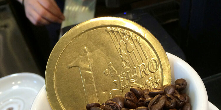 Foto de archivo. Un empleado usa una caja registradora, detrás de una moneda de chocolate en forma de  un euro en una taza de café, en Londres. 15 de octubre de 2014. REUTERS/Toby Melville.