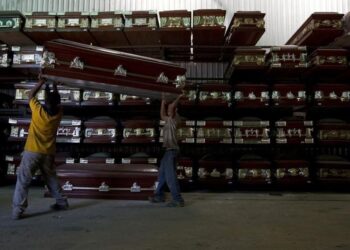 Workers carry a coffin in a caskets factory in Caracas November 29, 2012.REUTERS/Carlos Garcia Rawlins