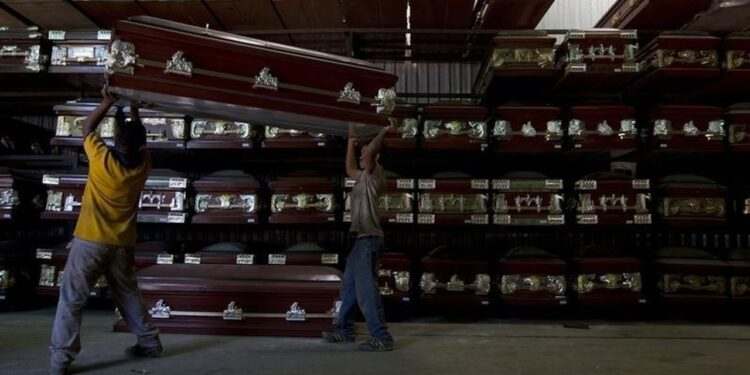 Workers carry a coffin in a caskets factory in Caracas November 29, 2012.REUTERS/Carlos Garcia Rawlins
