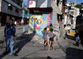 People walk pass a mural painted by Fabian Solymar in Petare slum, in Caracas, Venezuela August 7, 2019. Picture taken August 7, 2019. REUTERS/Manaure Quintero