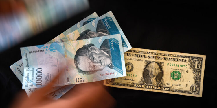 A man counts Venezuelan bolivar banknotes next to a US one-dollar bill in Caracas on August 2, 2018.
Venezuela's government on Thursday loosened the tight currency controls it first put in place 15 years ago, with the pro-government Constituent Assembly announcing the passage of a decree authorizing money exchange operations. / AFP PHOTO / Federico PARRA