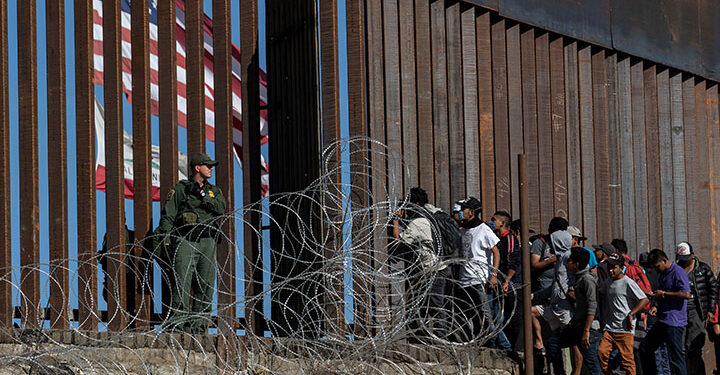 (FILES) In this file photo taken on November 25, 2018 Central American migrants look through a border fence as a US Border PatRol agents stands guard near the El Chaparral border crossing in Tijuana, Baja California State, Mexico. - Agence France-Press (AFP) photographer Guillermo Arias on September 7, 2019 won the top prize at photojournalism's biggest annual festival for his coverage of migrants from Central America. Arias, who is from Mexico, scooped the Visa d'Or for News, the most prestigious award handed out at the "Visa Pour L'Image" festival in Perpignan, southwestern France. (Photo by GUILLERMO ARIAS / AFP)