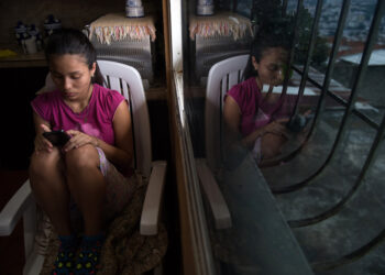 Venezuelan Dougliannys Perez, 15, whose parents emigrated, uses her cellphone after an interview with AFP, at Petare neighborhood in Caracas on August 9, 2019. - The crisis in Venezuela has broken up families since parents migrate to pay for the living of the children they leave behind. Some 850,000 children live without their parents in the country according to the NGO Cecodap. (Photo by Federico PARRA / AFP)