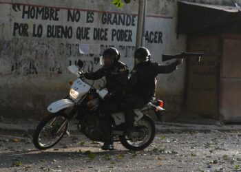 A riot policeman on a motorcycle points his gun during clashes with anti-government demonstrators in the neighborhood of Los Mecedores, in Caracas, on January 21, 2019. - A group of soldiers rose up against Venezuela's President Nicolas Maduro at a command post in northern Caracas on Monday, but were quickly arrested after posting an appeal for public support in a video, the government said. (Photo by Federico Parra / AFP)