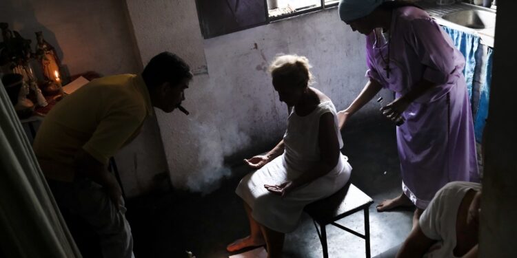 Venezuelan Esperanza Castillo (C), 74, is teated at the clinic of Venezuelan spiritual healer "Guayanese Brother" in Petare neighborhood, Caracas, on September 25, 2019. - Venezuelans turn to alternative treatments and the use of herbs to alleviate the disease conditions due to the lack or high cost of medicines. (Photo by Matias Delacroix / AFP)