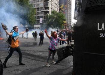 Demonstrators clash with riot police and army members in Santiago, on October 19, 2019. - Chile's president declared a state of emergency in Santiago Friday night and gave the military responsibility for security after a day of violent protests over an increase in the price of metro tickets. (Photo by Martin BERNETTI / AFP)
