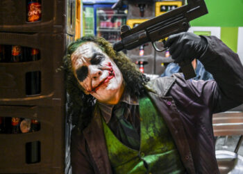 Venezuelan migrant Johnny Tales (R), who makes a living imitating the comicbook and film character "The Joker", poses at a convenience store in Medellin, on October 29, 2019. (Photo by JOAQUIN SARMIENTO / AFP)