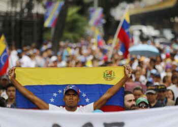 An opposition member holds a Venezuelan national flag during a protest march against President Nicolas Maduro in Caracas, Venezuela, Wednesday, Jan. 23, 2019. Venezuela's re-invigorated opposition faces a crucial test Wednesday as it seeks to fill streets nationwide with protesters in an appeal to the military and the poor to shift loyalties that until recently looked solidly behind Maduro's government. (AP Photo/Fernando Llano)