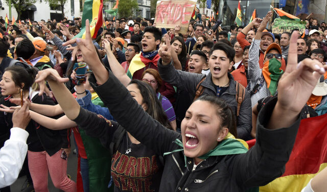 Supporters of Bolivia's main opposition presidential candidate, former president (2003-2005) Carlos Mesa, shout slogans against supporters of president and candidate Evo Morales, as both groups gather outside the hotel where the Supreme Electoral Tribunal has its headquarters to count the election votes, in La Paz, on October 21, 2019. - Evo Morales, seeking a controversial fourth term, led Bolivia's presidential election race Sunday but faces a historic second round run-off against Mesa, partial results showed. Morales had 45 percent of the vote to Mesa's 38 percent, the Supreme Electoral Tribunal announced, with most of the votes counted. (Photo by Aizar RALDES / AFP)