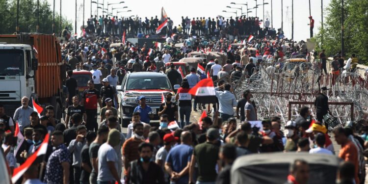 Iraqi protesters gather on the capital Baghdad's Al-Jumhuriyah Bridge on October 26, 2019, during an anti-government protest. - Iraqi security forces fired tear gas to clear lingering protesters in Baghdad this morning, after dozens died in a bloody resumption of anti-government rallies to be discussed in parliament. (Photo by - / AFP)