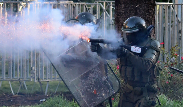 A policeman shoots at demonstrators during a protest against the government in Santiago on November 26, 2019. - The organization Human Rights Watch (HRW) presented Tuesday a report denouncing serious human rights violations by the Chilean police. (Photo by Johan ORDONEZ / AFP)