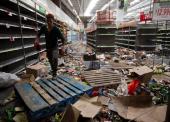 A worker is seen inside a looted supermarket in Santiago on November 28, 2019. - Looters sacked supermarkets in Chile in another night of unrest Tuesday as tensions flared in the South American country, after over 40 days of social crisis. (Photo by CLAUDIO REYES / AFP)