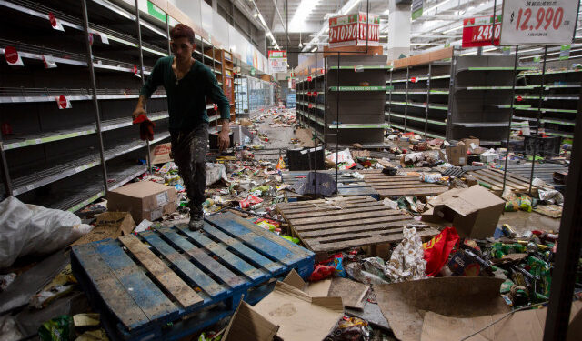 A worker is seen inside a looted supermarket in Santiago on November 28, 2019. - Looters sacked supermarkets in Chile in another night of unrest Tuesday as tensions flared in the South American country, after over 40 days of social crisis. (Photo by CLAUDIO REYES / AFP)