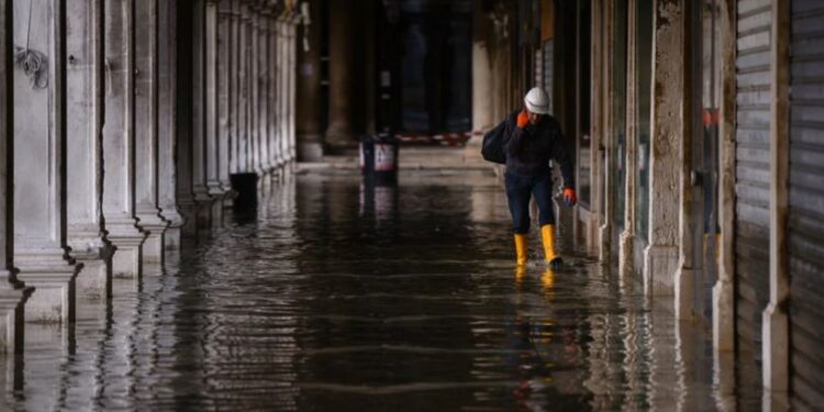 Un hombre con botas camina en Venecia. (AFP)