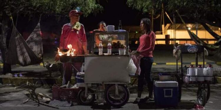 Migrantes venezolanos dirigen un puesto de comida callejera en una terminal de autobuses en Maicao, La Guajira, en el norte de Colombia. Fotografía Bloomberg.