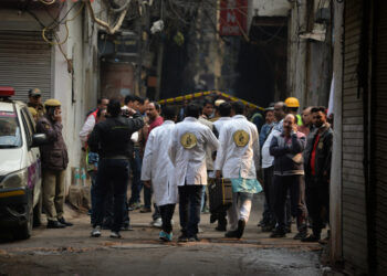 A forensics team walks along a street leading to a factory site where a fire broke out, in Anaj Mandi area of New Delhi on December 8, 2019. - At least 43 people have died in a factory fire in India's capital New Delhi, with the toll expected to rise, police told AFP. The blaze broke out in the early hours in the city's old quarter, whose narrow and congested lanes are lined with many small manufacturing and storage units. (Photo by Sajjad  HUSSAIN / AFP)