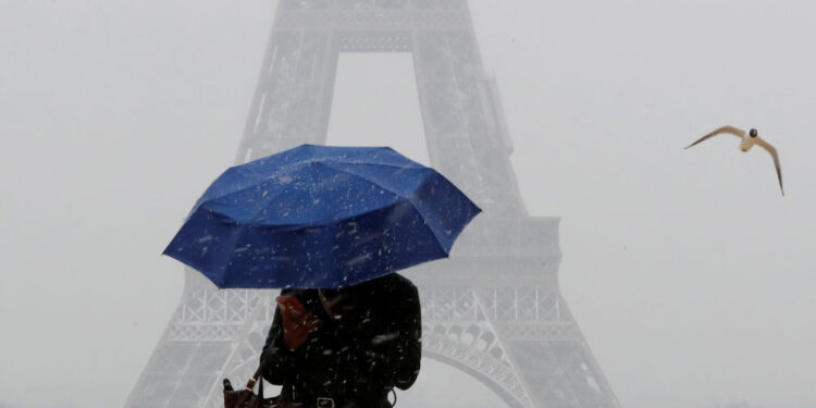 A woman holds an umbrella to protect herself from falling snow near the Eiffel Tower in Paris, as winter weather with snow and freezing temperatures arrive in France, February 6, 2018. REUTERS/Gonzalo Fuentes - RC12AF5ABA60