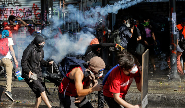 Demonstrators clash with riot police during a protest against the government and to commemorate the first anniversary of the death of Mapuche indigenous leader Camilo Castrillanca -killed in a police operation- in Santiago, on November 14, 2019. - The demonstrators are demanding greater social reform from President Sebastian Pinera, who has announced several measures in a bid to appease protesters, including a pledge to change the constitution that dates from the 1973-90 Augusto Pinochet dictatorship. (Photo by JAVIER TORRES / AFP)