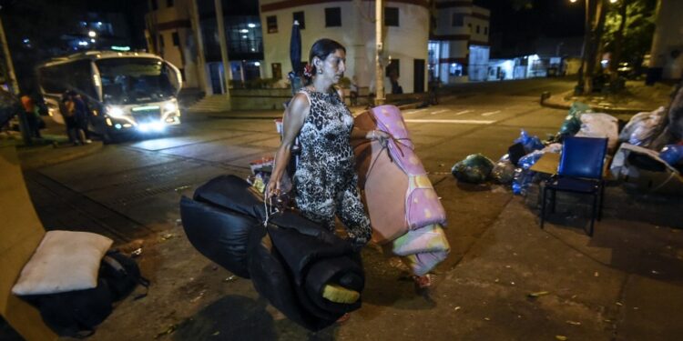(FILES) In this file picture taken on December 18, 2019 A Venezuelan migrant carries mattresses to rest at a park in Bucaramanga, Colombia. - Dozens of Venezuelan migrants have turned the Colombian city of Bucaramanga into a large open-air bedroom. Several of the city's 244 parks are transformed into improvised camps at night. (Photo by Juan BARRETO / AFP)