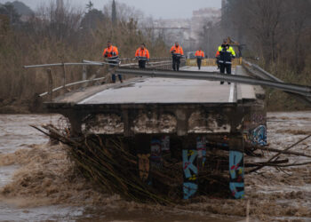 Policemen and security members walk on a fallen bridge in Malgrat de Mar, near Girona on January 22, 2020, as storm Gloria batters Spanish eastern coast. - - A winter storm which has killed three people lashed much of eastern Spain for a third day yesterday, cutting power, forcing the closure of schools and severing road and rail links. National weather agency Aemet placed most of northeastern Spain on alert because of the storm packing gusts of over 100 kilometres (60 miles) per hour, heavy snowfall, freezing rain and massive waves which smashed into seafront promenades, damaging shops and restaurants. (Photo by Josep LAGO / AFP)