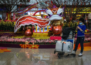 A traveller wearing a face mask as a precautionary measure to protect against the possible spread of a SARS-like virus outbreak stands in the arrivals area at Hong Kong International Airport ahead of the Chinese New Year in Hong Kong on January 23, 2020. - Hong Kong has turned two holiday camps, including a former military barracks, into quarantine zones for people who may have come into contact with carriers of the Wuhan virus, officials announced on January 23. The international financial hub has been on high alert for the virus, which has killed 17 people since the outbreak started in central China. (Photo by VIVEK PRAKASH / AFP)