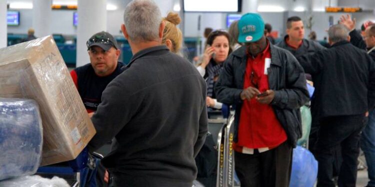 La gente espera en la fila con el equipaje envuelto en plástico antes de registrarse en un vuelo chárter de Havana Air a Cuba. NICK SWYTER MIAMI HERALD STAFF