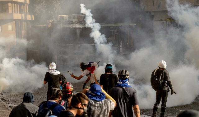 Demonstrators clash with riot police during a protest against the government of President Sebastian Pinera, in Santiago, on January 24, 2020. - Demonstrations which began on October 18, 2019, initially against a modest metro fare hike, quickly escalated and left 29 people dead amid accusations of a heavy-handed response from security forces. (Photo by Martin BERNETTI / AFP)