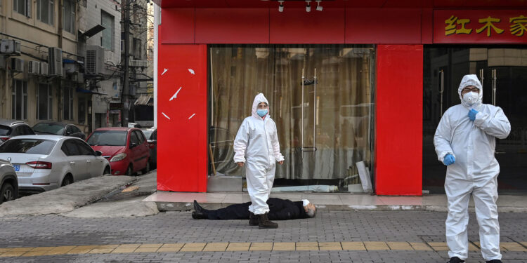 EDITORS NOTE: Graphic content / This photo taken on January 30, 2020 shows officials in protective suits checking on an elderly man wearing a facemask who collapsed and died on a street near a hospital in Wuhan. - AFP journalists saw the body on January 30, not long before an emergency vehicle arrived carrying police and medical staff in full-body protective suits. The World Health Organization declared a global emergency over the new coronavirus, as China reported on January 31 the death toll had climbed to 213 with nearly 10,000 infections. (Photo by Hector RETAMAL / AFP) / TO GO WITH China-health-virus-death,SCENE by Leo RAMIREZ and Sebastien RICCI