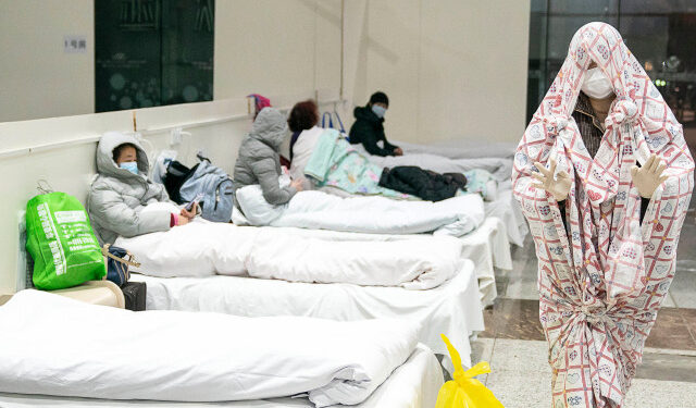 This photo taken on February 5, 2020 shows a patient (R) covered with a bed sheet at an exhibition centre converted into a hospital as it starts to accept patients displaying mild symptoms of the novel coronavirus in Wuhan in China's central Hubei province. - China scrambled to find bed space for thousands of newly infected patients on February 6, as the toll from a deadly new virus jumped again with more than 28,000 people known infected nationwide and 563 deaths. (Photo by STR / AFP) / China OUT