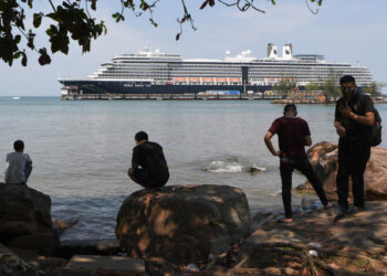 People watch the Westerdam cruise ship in Sihanoukville on February 19, 2020. - Dozens of passengers stuck for nearly a week on a US cruise ship in Cambodia disembarked on February 19, after being given the all-clear from the deadly COVID-19 novel coronavirus. (Photo by TANG CHHIN Sothy / AFP)