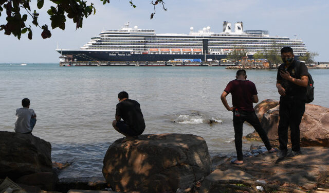 People watch the Westerdam cruise ship in Sihanoukville on February 19, 2020. - Dozens of passengers stuck for nearly a week on a US cruise ship in Cambodia disembarked on February 19, after being given the all-clear from the deadly COVID-19 novel coronavirus. (Photo by TANG CHHIN Sothy / AFP)