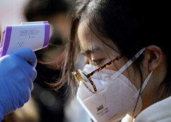 Un trabajador le toma la temperatura a una mujer en una fábrica de Shanghai, en China, el 31 de enero de 2020, en medio de una preocupación mundial por la expansión del coronavirus. REUTERS/Aly Song