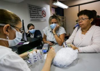 Women buy face masks, alcohol and disinfectant solutions at a pharmacy clerk as Venezuelans rush to buy hand sanitizers and masks in the face of the global COVID-19 coronavirus pandemic, in Caracas, on March 13, 2020. (Photo by CRISTIAN HERNANDEZ / AFP)