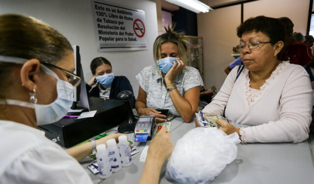 Women buy face masks, alcohol and disinfectant solutions at a pharmacy clerk as Venezuelans rush to buy hand sanitizers and masks in the face of the global COVID-19 coronavirus pandemic, in Caracas, on March 13, 2020. (Photo by CRISTIAN HERNANDEZ / AFP)