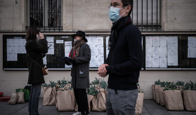 A member of an AMAP (association for the preservation of local farming) waits for others to come and pick up their weekly basket of fresh locally farmed vegetables in Paris on March 18, 2020 as a strict lockdown came into in effect in France to stop the spread of the COVID-19 disease caused by the novel coronavirus. (Photo by Philippe LOPEZ / AFP)