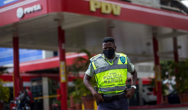 A member of Baruta Municipal Police stands guard near a gas station wearing a face mask as a precautionary measure against the spread of the new coronavirus, COVID-19, in Caracas on March 23, 2020. - Venezuela is facing the novel coronavirus pandemic while suffering a major gasoline shortage and with the country's water system collapsed, which has left many homes without running water. (Photo by Cristian Hernandez / AFP)