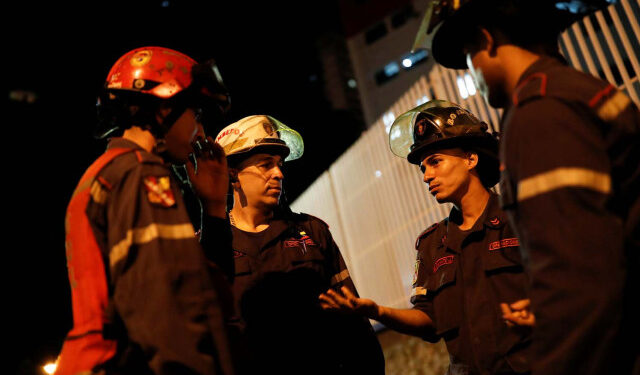 Firefighters talk in the surrounding area of the skyscraper known as the "Tower of David" after an earthquake in Caracas, Venezuela August 21, 2018. REUTERS/Carlos Garcia Rawlins