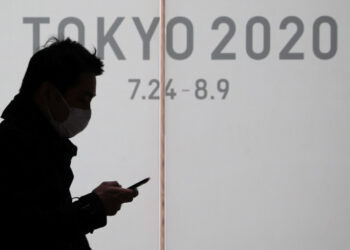 Un hombre porta una mascarilla para protegerse de la epidemia de coronavirus mientras pasa frente a un cartel que anuncia los Juegos Olímpicos de Tokio 2020. Marzo 3, 2020. REUTERS/Stoyan Nenov