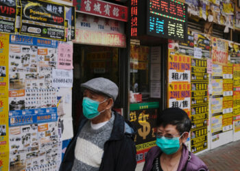 People wearing protective masks walk past closed shops covered with advertisements for rental space at Mongkok, following the outbreak of the new coronavirus, in Hong Kong, China March 13, 2020. REUTERS/Tyrone Siu