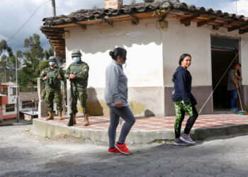 Soldiers stand guard as residents cross a street near the Ecuadoran side of a border crossing with Colombia, in Tufino, Ecuador, after Ecuador's government announced the closure of its borders from Sunday to all foreign travelers due to the spread of the coronavirus (COVID-19), March 15, 2020. REUTERS/Daniel Tapia