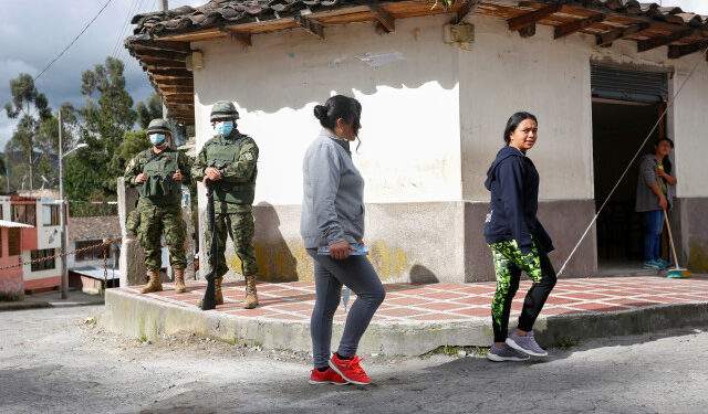 Soldiers stand guard as residents cross a street near the Ecuadoran side of a border crossing with Colombia, in Tufino, Ecuador, after Ecuador's government announced the closure of its borders from Sunday to all foreign travelers due to the spread of the coronavirus (COVID-19), March 15, 2020. REUTERS/Daniel Tapia