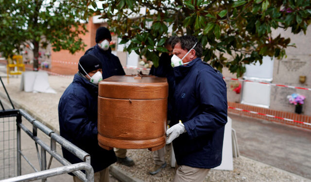 Employees of a mortuary carry the coffin of a person who died from the coronavirus disease (COVID-19), during the partial lockdown to combat the disease outbreak, at the Carabanchel cemetery in Madrid, Spain, March 27, 2020. REUTERS/Juan Medina