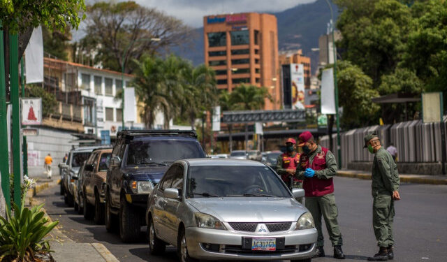 Members of the National Bolivarian Guard control a queue of drivers trying to refuel the tnaks of their cars near a gas station in Caracas on March 23, 2020. - Venezuela is facing the novel coronavirus pandemic while suffering a major gasoline shortage and with the country's water system collapsed, which has left many homes without running water. (Photo by Cristian Hernandez / AFP)