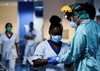 Medical workers put on their protective gears before working on March 27, 2020, at the unit for coronavirus COVID-19 infected patients at the Erasme Hospital in Brussels. (Photo by Kenzo TRIBOUILLARD / AFP)